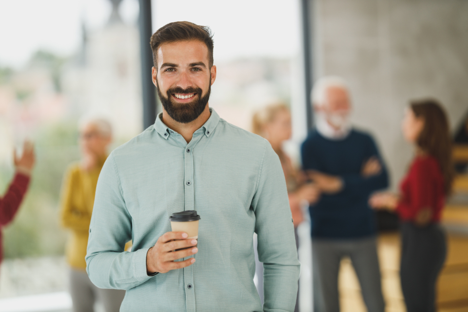 Jeune actif souriant, un café à la main